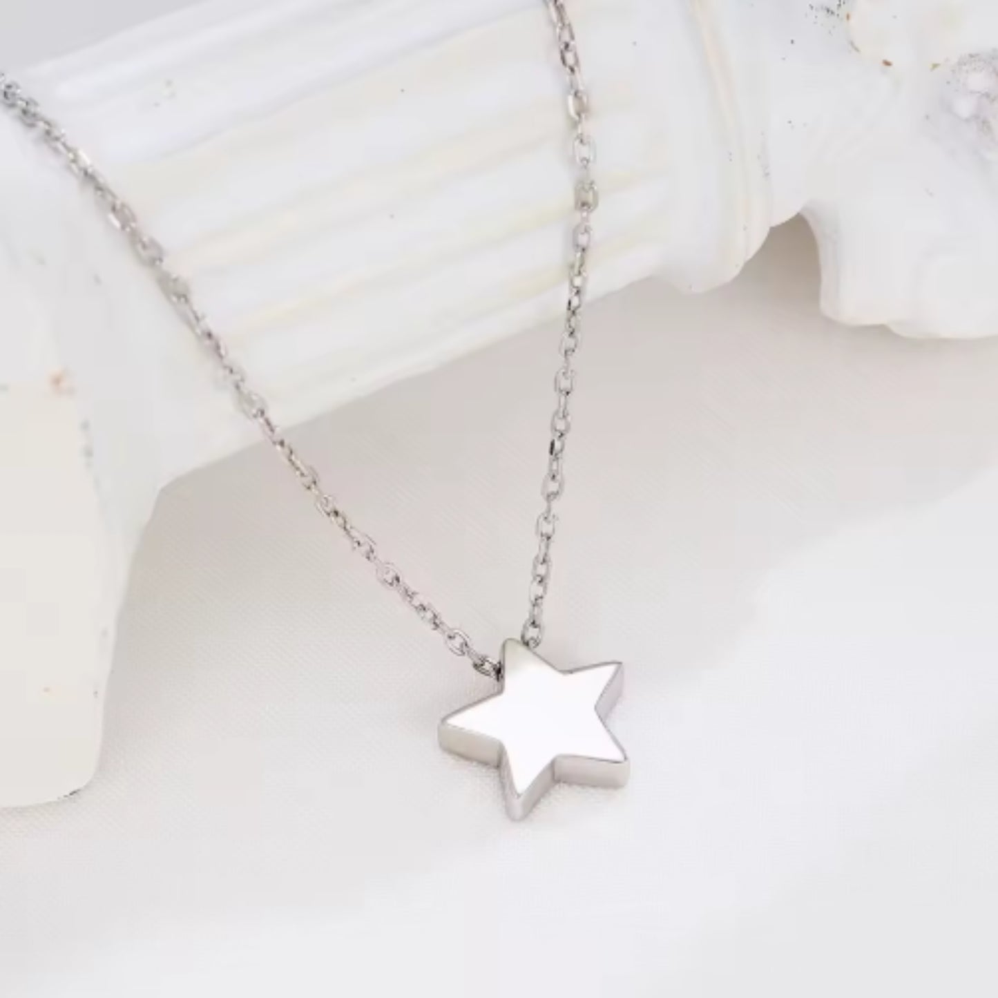 Radiant Star Necklace displayed on a white surface, highlighting its minimalist silver star pendant design.