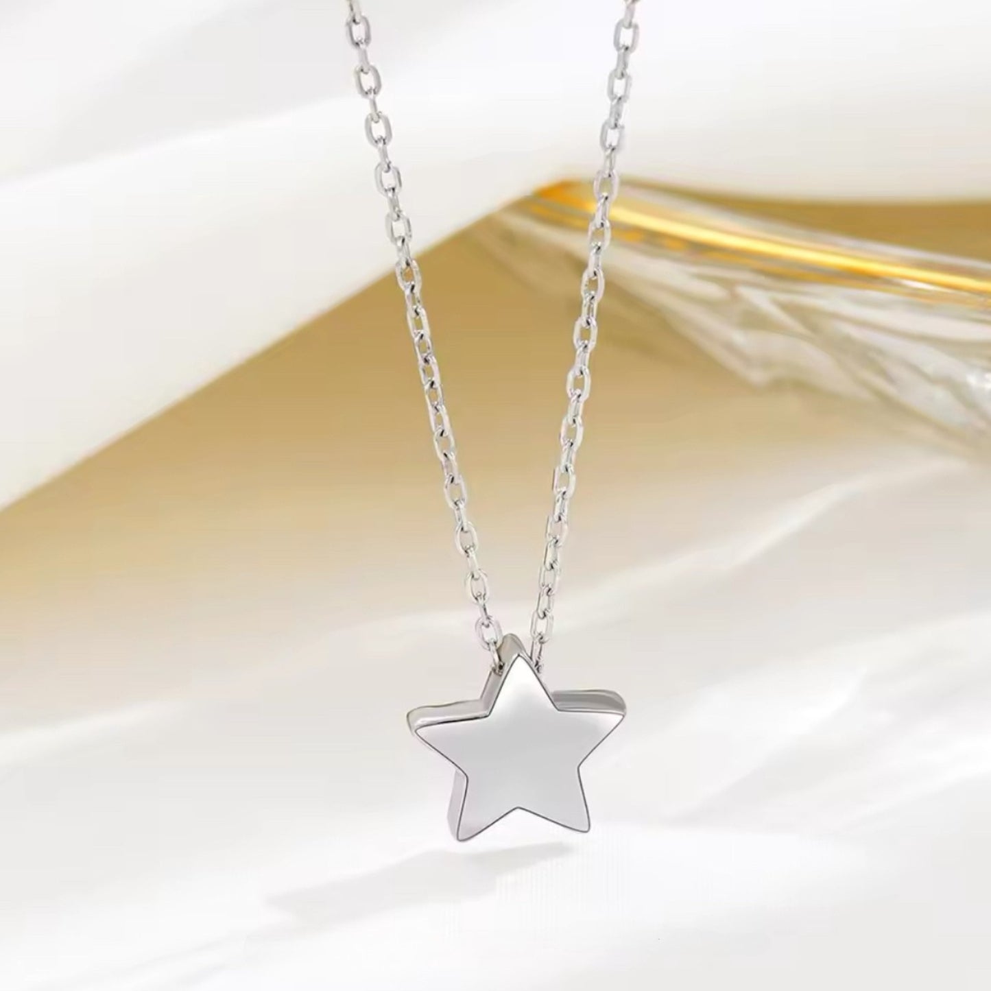 Radiant Star Necklace resting on a soft fabric background, emphasizing its polished silver star pendant.