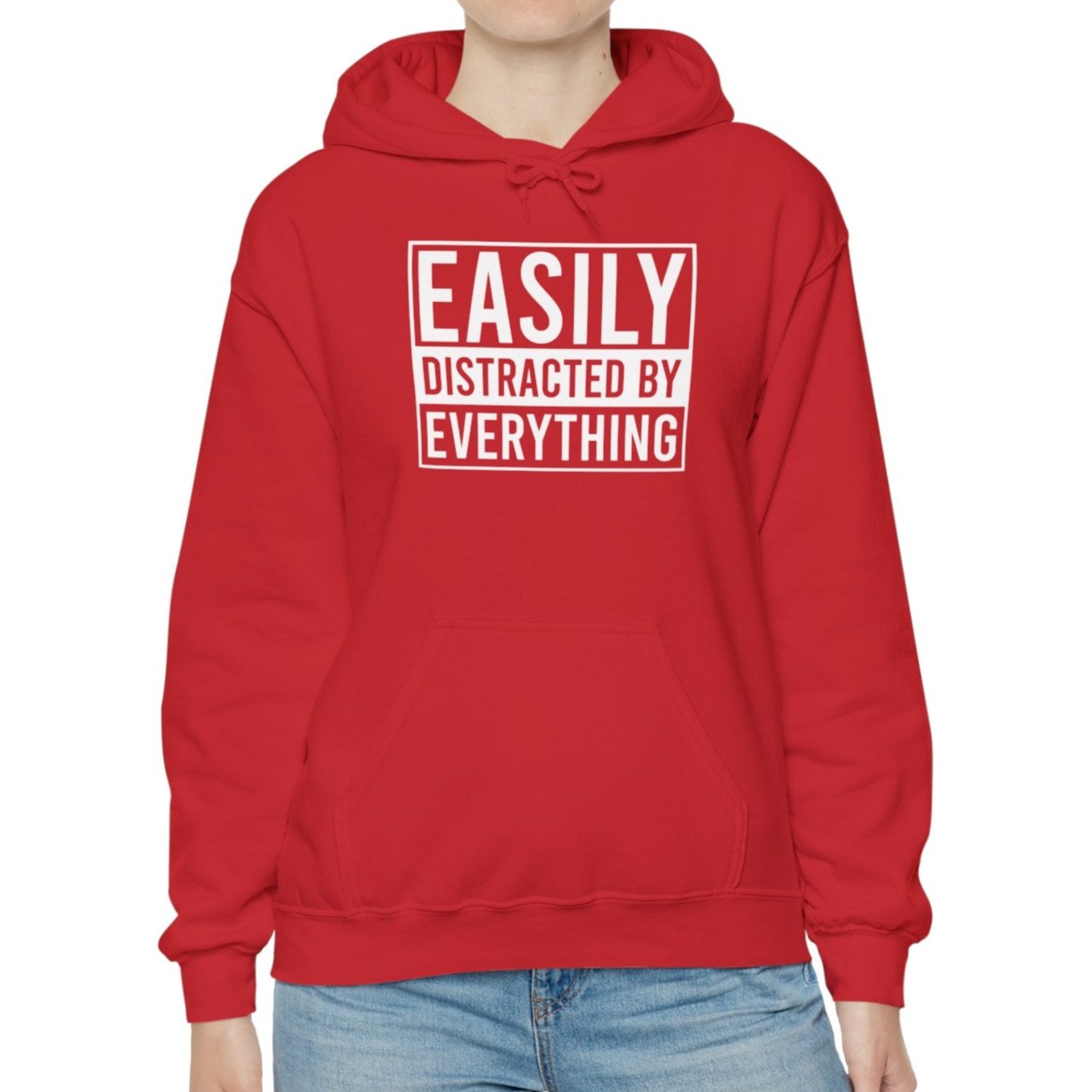 Model wearing a red hoodie with the text "Easily Distracted by Everything" in bold white lettering. Part of the Vivid Divergence Sensory Friendly Unisex Hoodie Range.