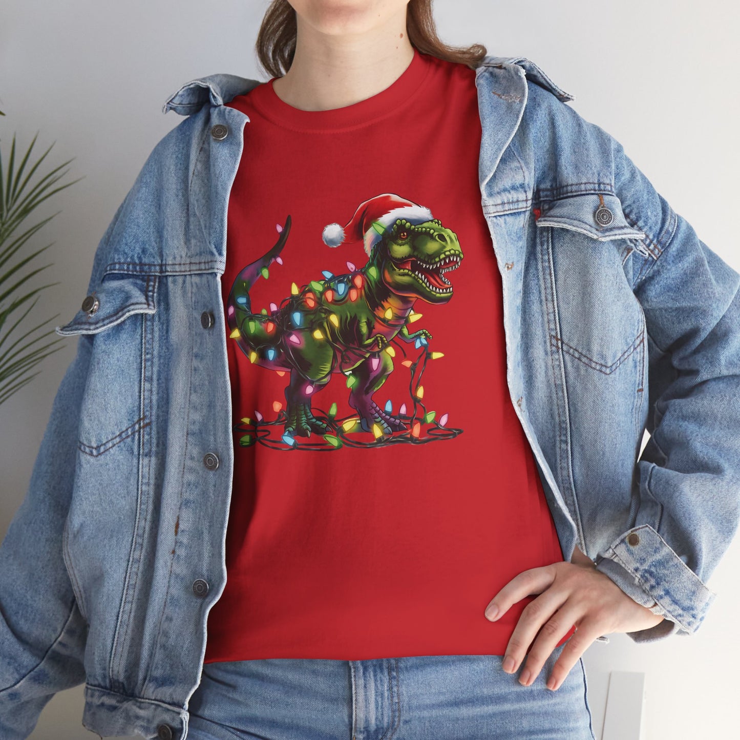Model wearing a red T-shirt with a festive T-Rex tangled in Christmas lights, paired with a denim jacket. Part of the Vivid Divergence Sensory Friendly Unisex Tees Range.