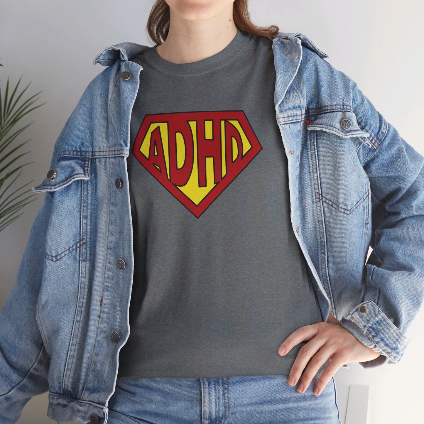 Styled look featuring a grey T-shirt with a yellow and red ADHD logo styled in the Superman symbol, worn under a denim jacket. Part of the Vivid Divergence Sensory Friendly Unisex Tees Range.