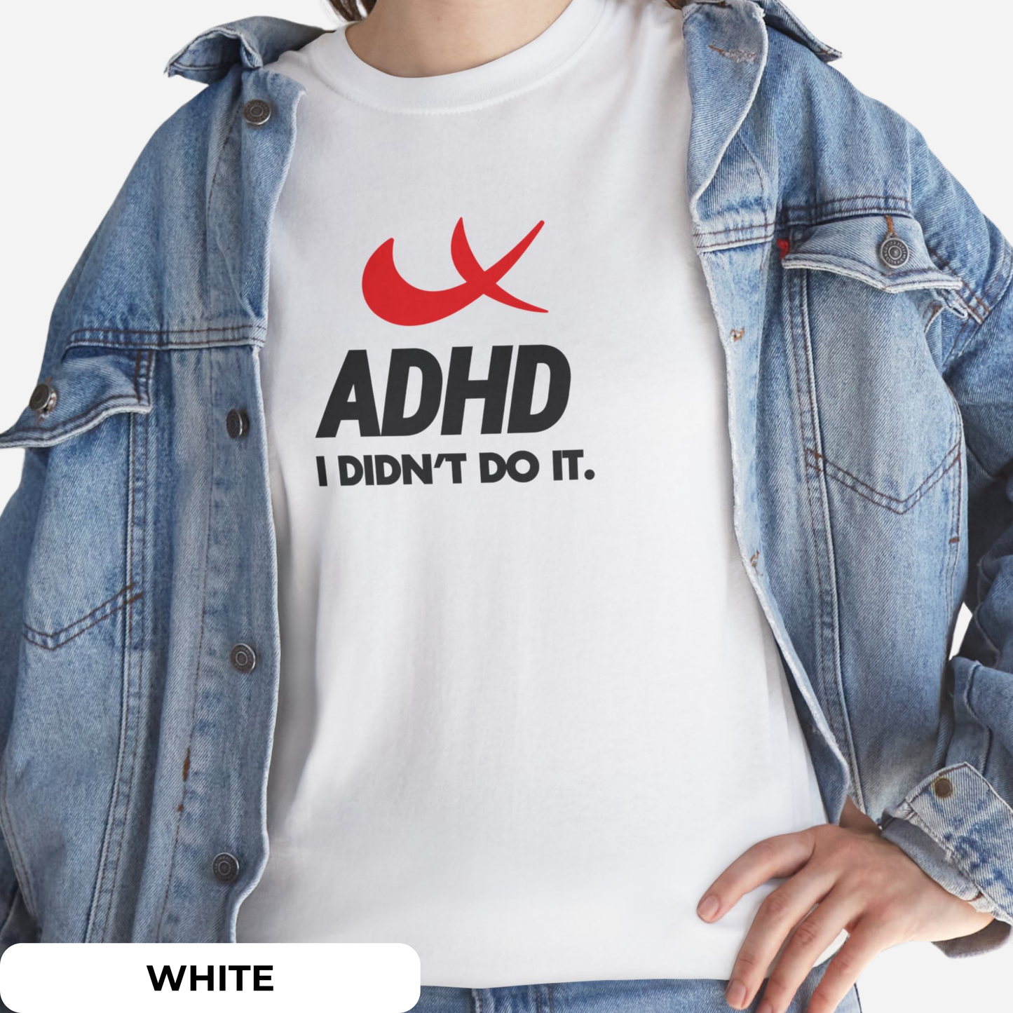 Styled look featuring a white T-shirt with "ADHD I Didn't Do It" phrase and red swoosh parody of the Nike symbol, worn under a denim jacket. Part of the Vivid Divergence Sensory Friendly Unisex Tees Range