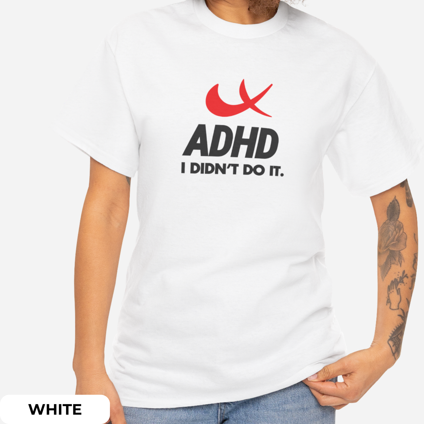 Side view of a white T-shirt featuring the phrase "ADHD I Didn't Do It" with a red swoosh parody of the Nike symbol. Part of the Vivid Divergence Sensory Friendly Unisex Tees Range.