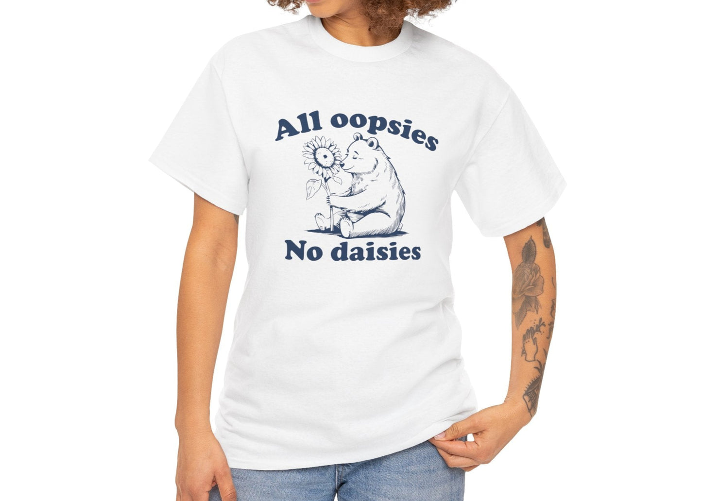 Model wearing a white T-shirt with "All oopsies, no daisies" and a playful bear graphic in teal text. Part of the Vivid Divergence Sensory Friendly Unisex Tees Range.