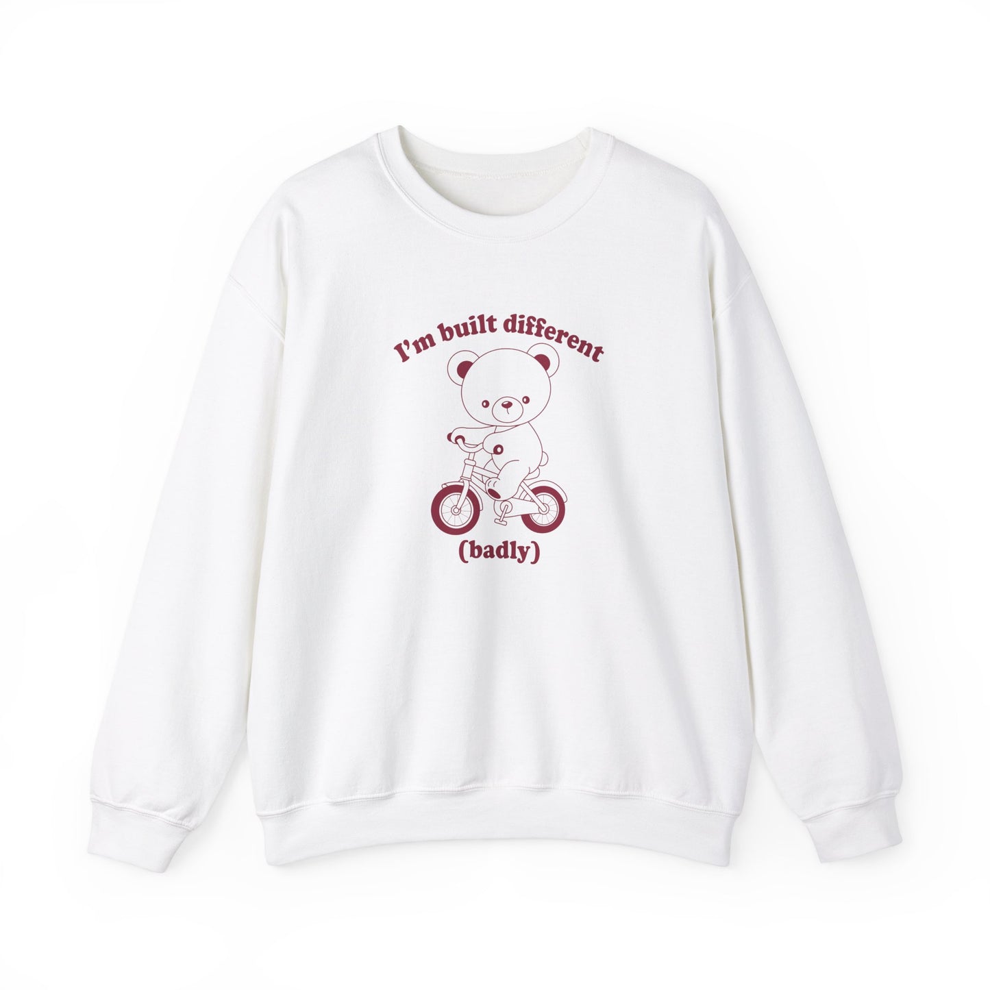 Front view of a white sweatshirt featuring a graphic of a bear riding a bike with the text "I'm Built Different (Badly)." Part of the Vivid Divergence Sensory Friendly Unisex Sweater Jumper Range.