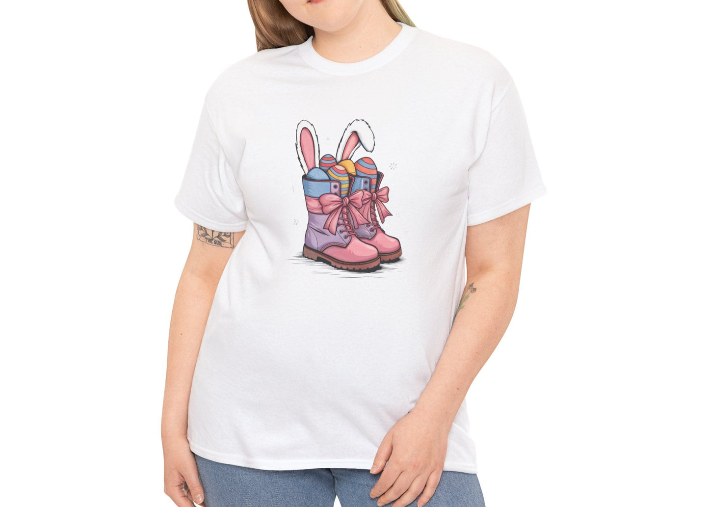 Woman wearing a White Easter T-shirt featuring a fun cowgirl boots design with bunny ears and pastel eggs, a festive choice for spring. Hop into the season in style and shop Easter shirts online today!