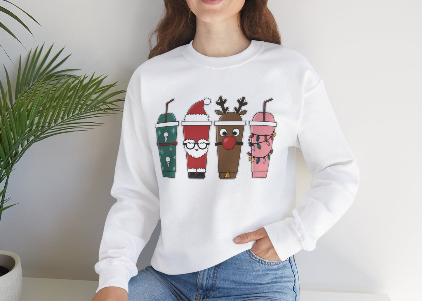 Lifestyle image of a white sweatshirt with Christmas-themed iced coffee illustrations worn in a cozy indoor setting. Part of the Vivid Divergence Sensory Friendly Unisex Sweater Jumper Range.