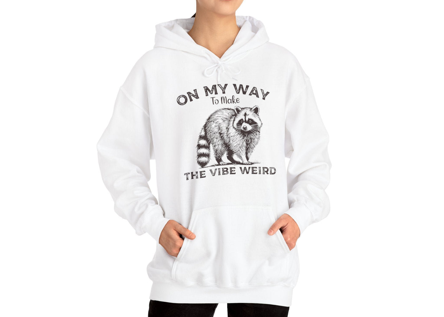 Model wearing a white hoodie featuring the text "On My Way to Make the Vibe Weird" and a cartoon illustration of a raccoon holding a stick. Part of the Vivid Divergence Sensory Friendly Unisex Hoodie Range.
