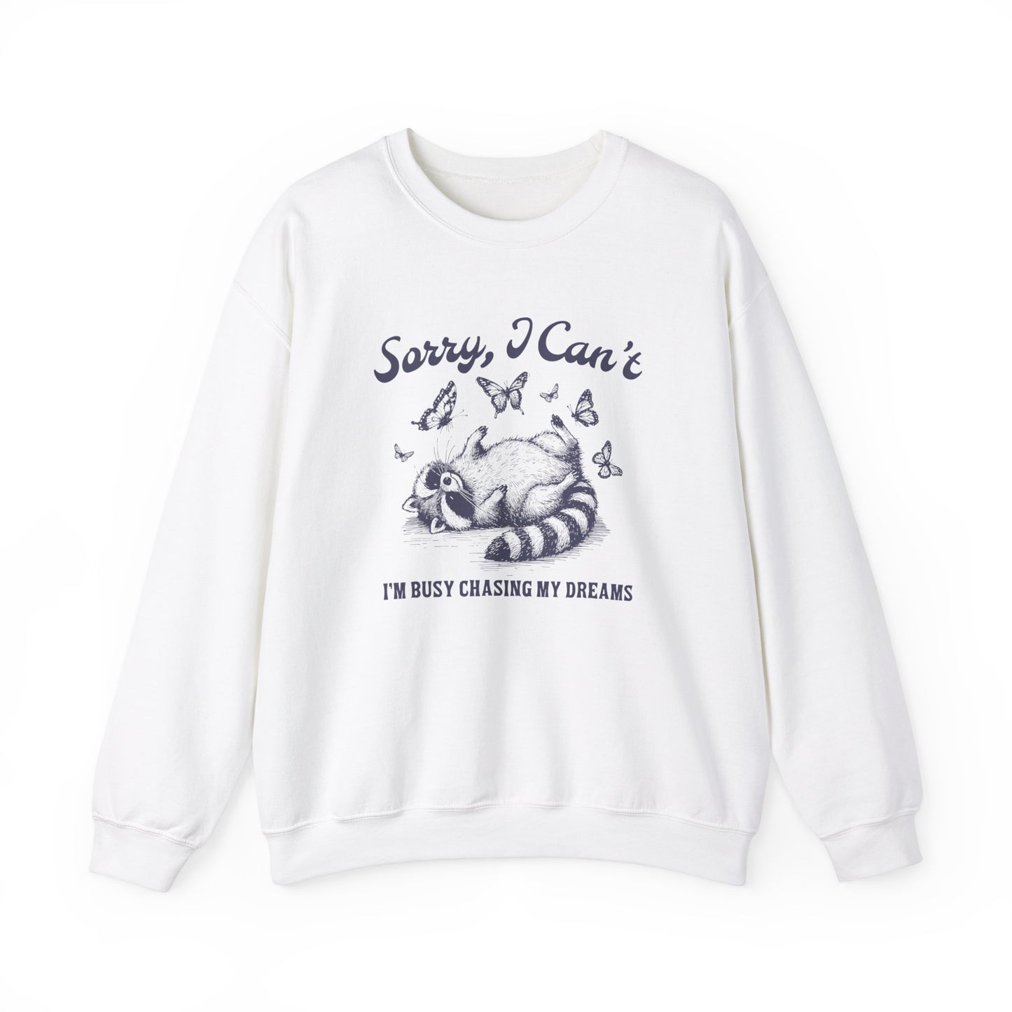Front view of a white sweater jumper with the text "Sorry, I Can't. I'm Busy Chasing My Dreams" and a cartoon raccoon illustration sleeping on a crescent moon. Part of the Vivid Divergence Sensory Friendly Unisex Sweater Jumper Range.