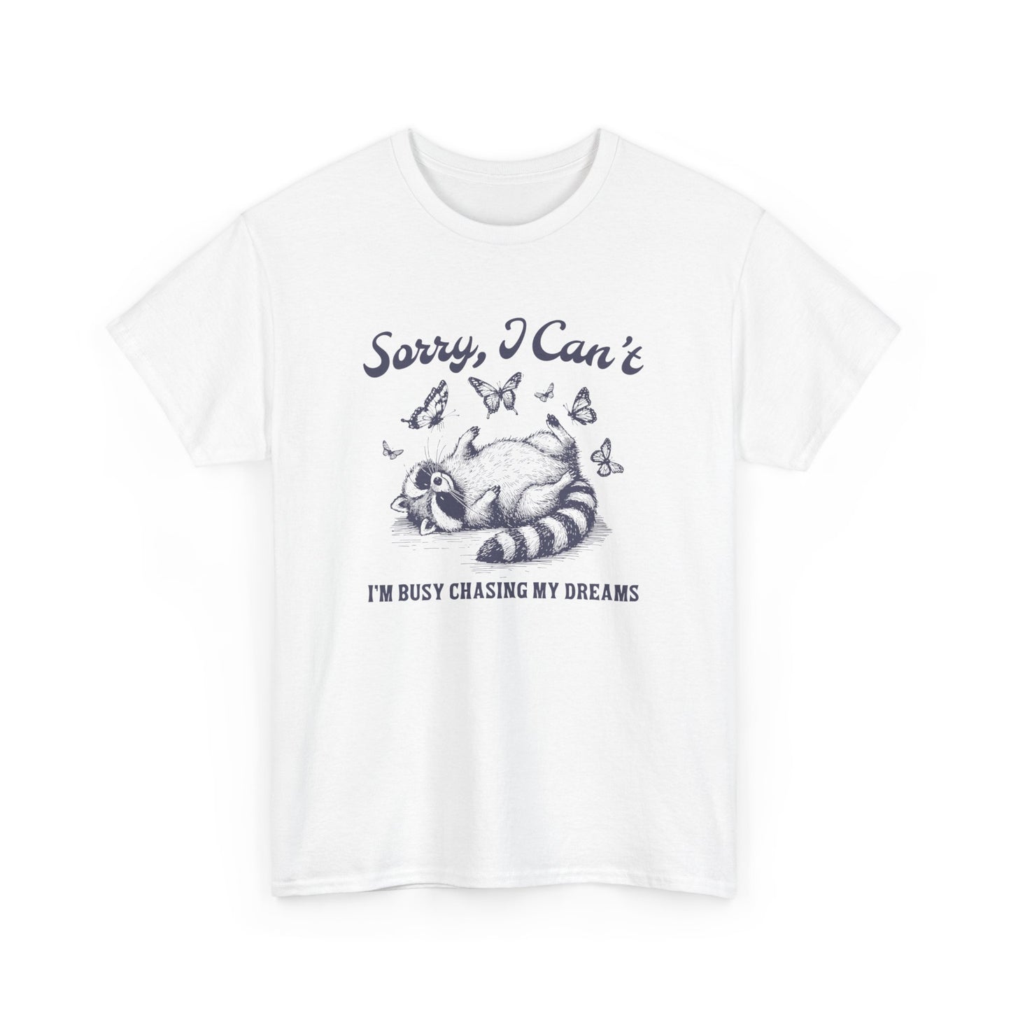 Front view of a white T-shirt with "Sorry I Can't, I'm Busy Chasing My Dreams" and a playful sleeping raccoon graphic in black text. Part of the Vivid Divergence Sensory Friendly Unisex Tees Range.
