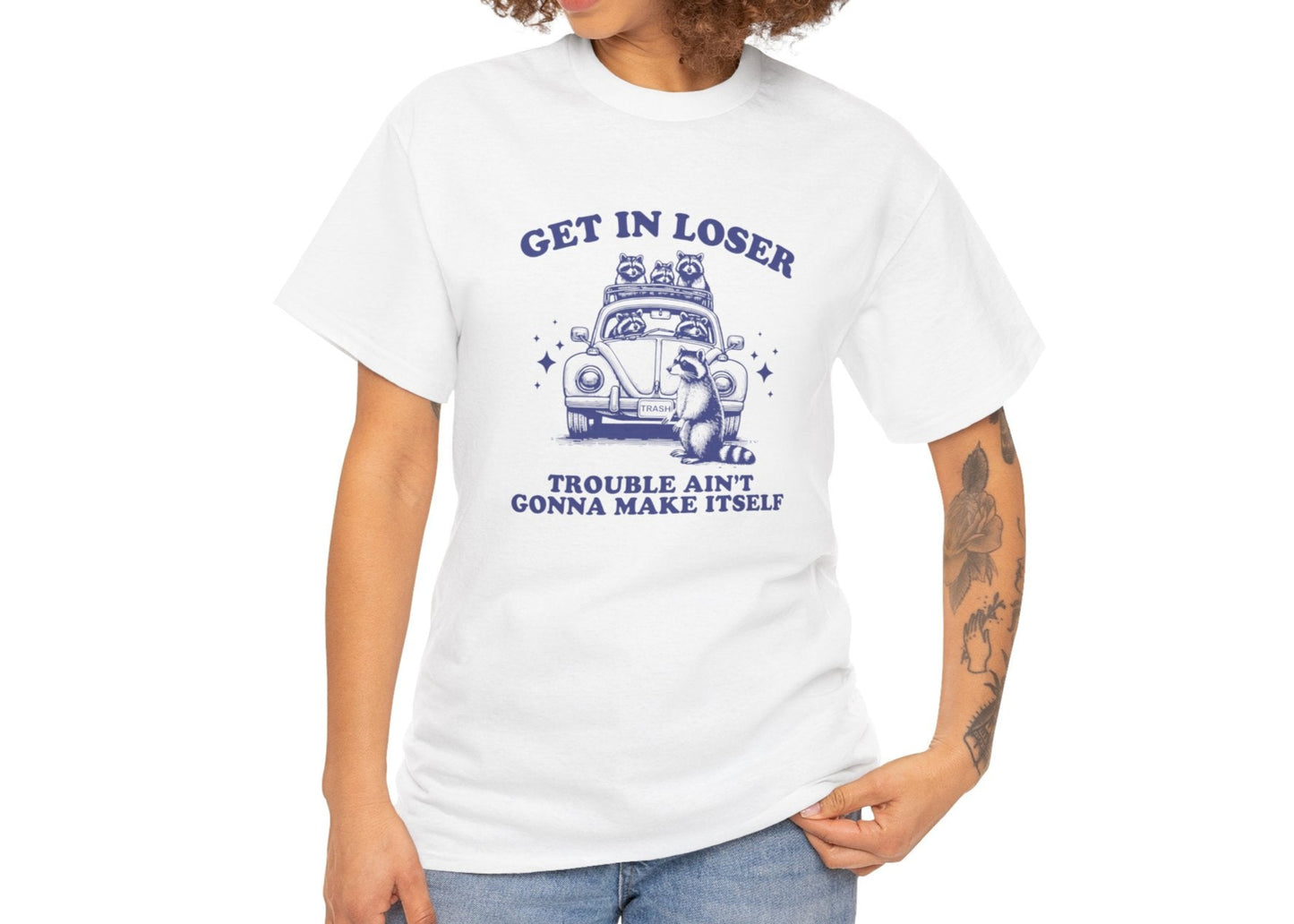 Modeled front view of a white T-shirt featuring blue text and an illustration of cute raccoons in a vintage car that reads "Get In Loser, Trouble Ain't Gonna Make Itself." Part of the Vivid Divergence Sensory Friendly Unisex Tees Range.