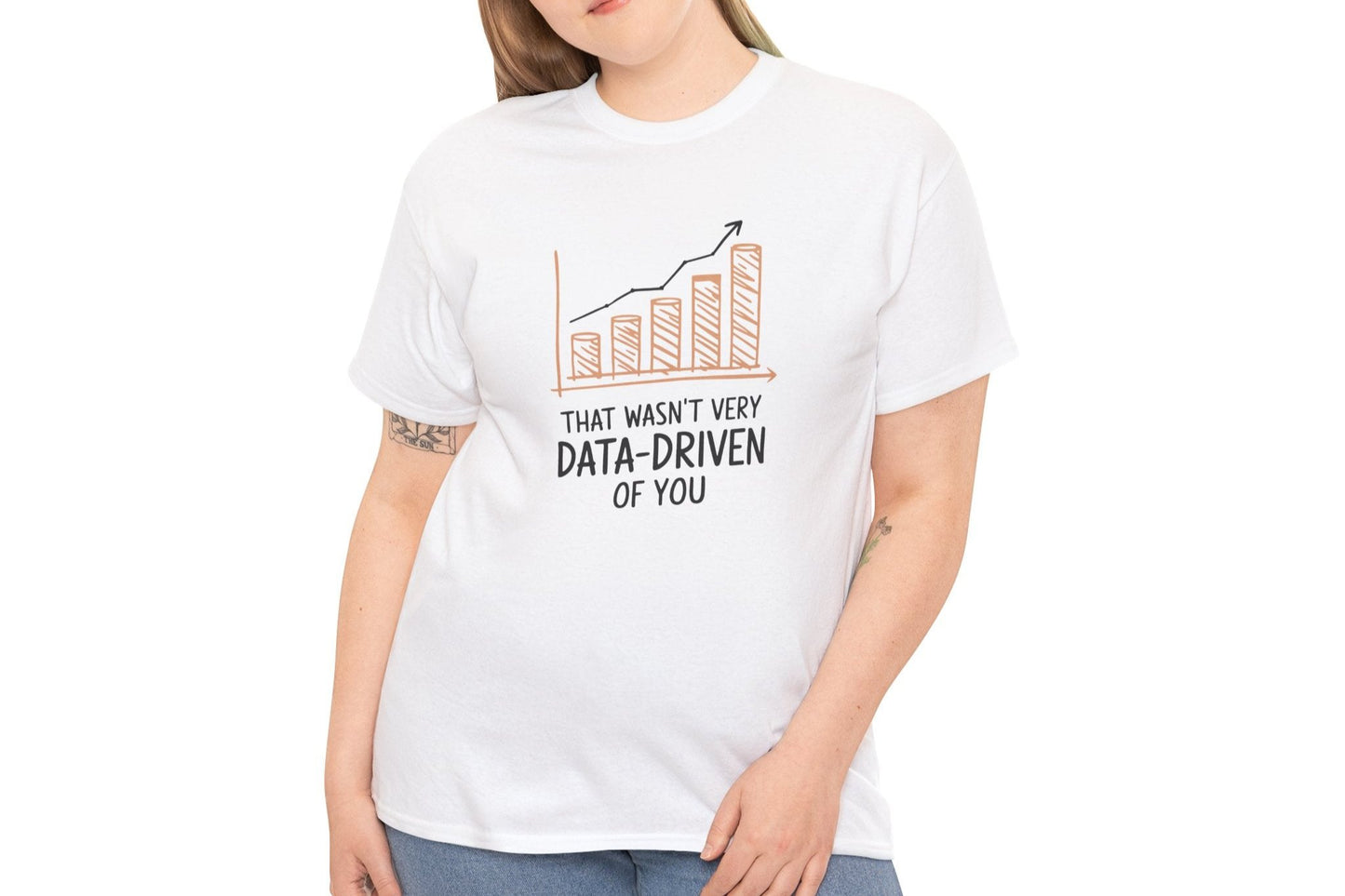 Model wearing a white T-shirt with the text "That Wasn't Very Data-Driven of You" in black, featuring a graphic of a declining bar chart in orange. Part of the Vivid Divergence Sensory Friendly Unisex Tees Range.