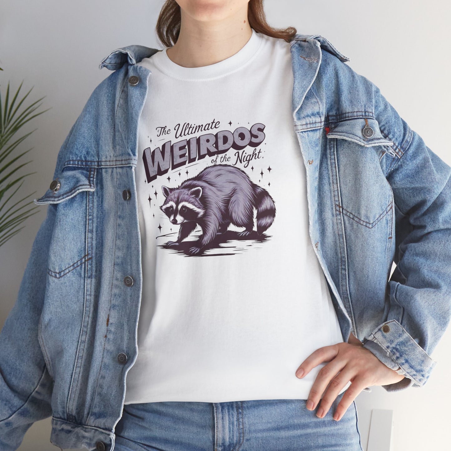 Model wearing a white T-shirt with "Weirdos of the Night" and an illustrated raccoon graphic in bold purple and black text, styled with a denim jacket. Part of the Vivid Divergence Sensory Friendly Unisex Tees Range.