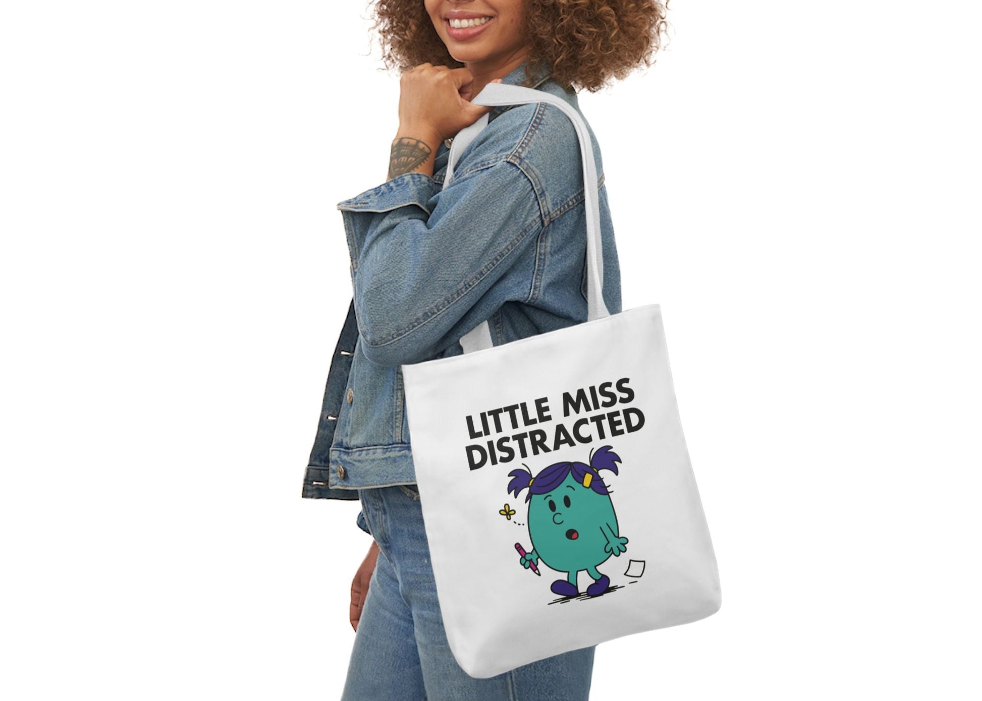 Woman in denim modeling the Little Miss Distracted tote bag on her shoulder. She walked into the room and forgot why. Part of the Vivid Divergence Little Miss Meme Collection!
