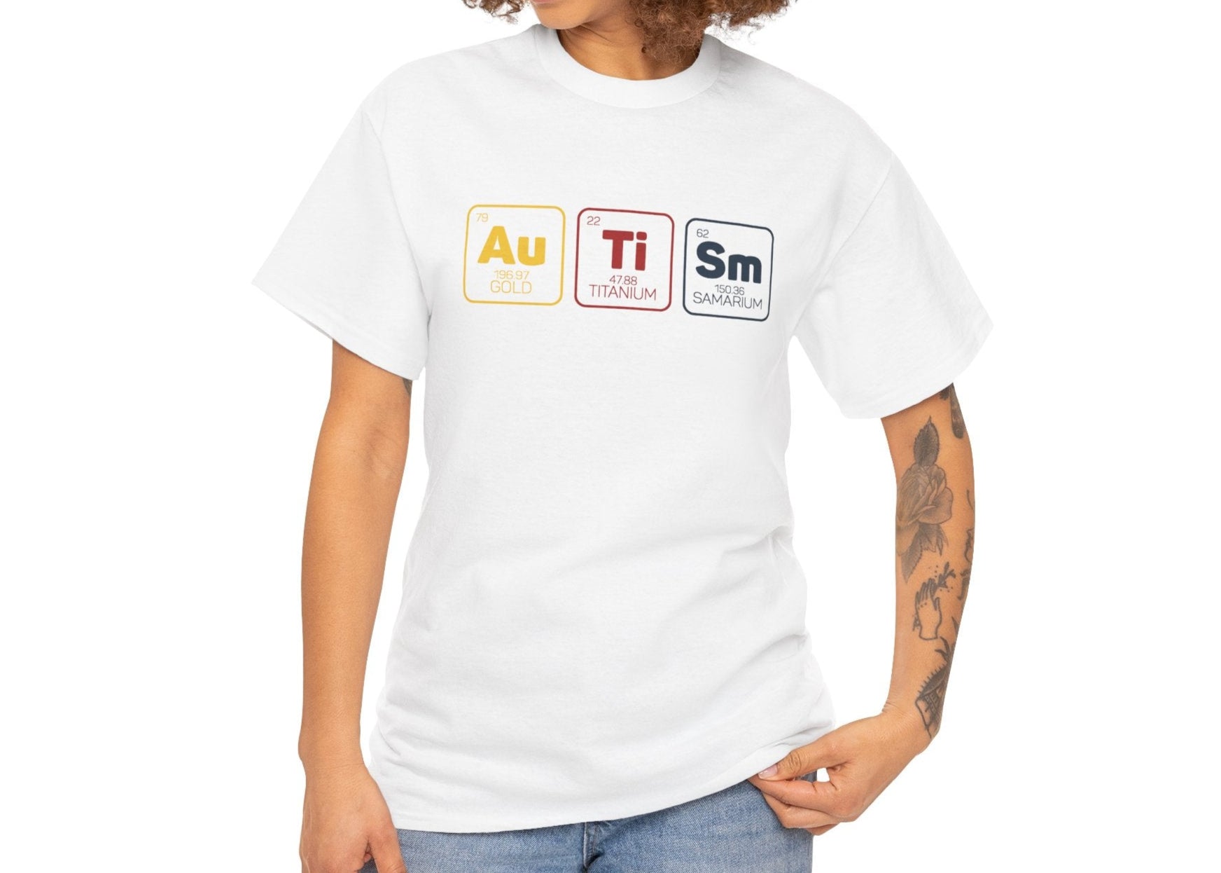 Woman with curly hair wearing a white "Au Ti Sm" periodic table Autism T-shirt, smiling and posing casually. Part of the Vivid Divergence Sensory Friendly Unisex Tees Range.
