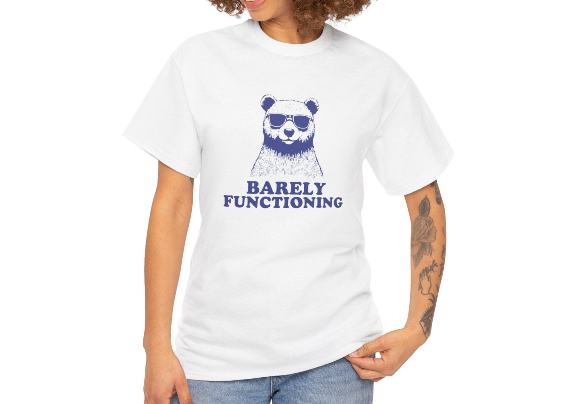 Female model wearing a white T-shirt with a blue bear graphic and "Barely Functioning" text. Part of the Vivid Divergence Sensory Friendly Unisex Tees Range.