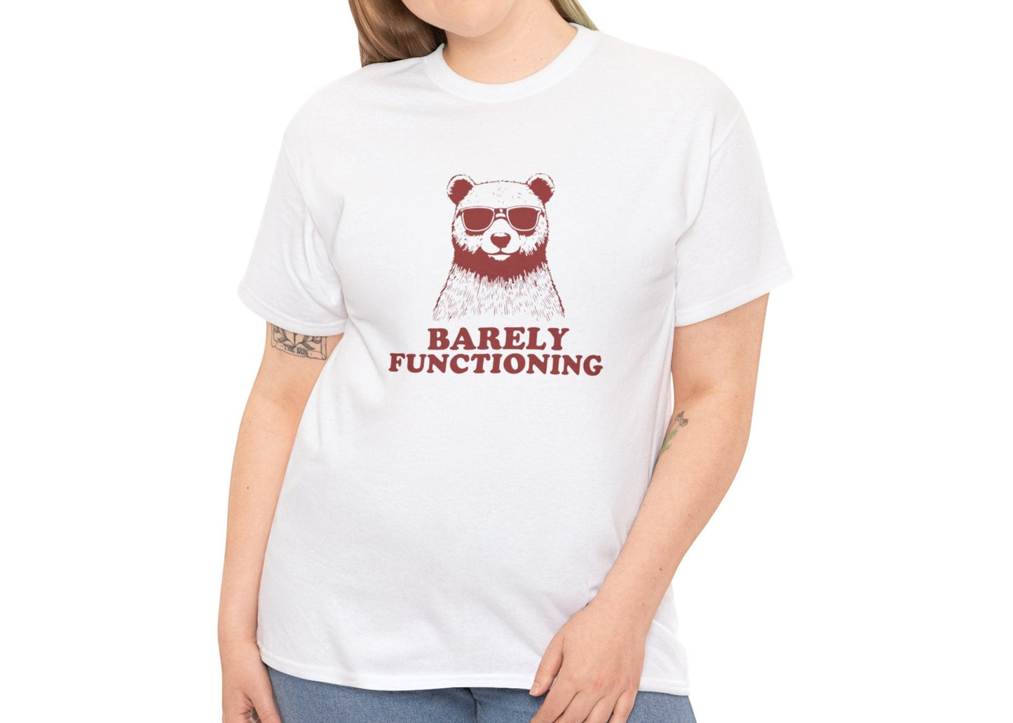 Female model wearing a white T-shirt with a red bear graphic and "Barely Functioning" text. Part of the Vivid Divergence Sensory Friendly Unisex Tees Range.