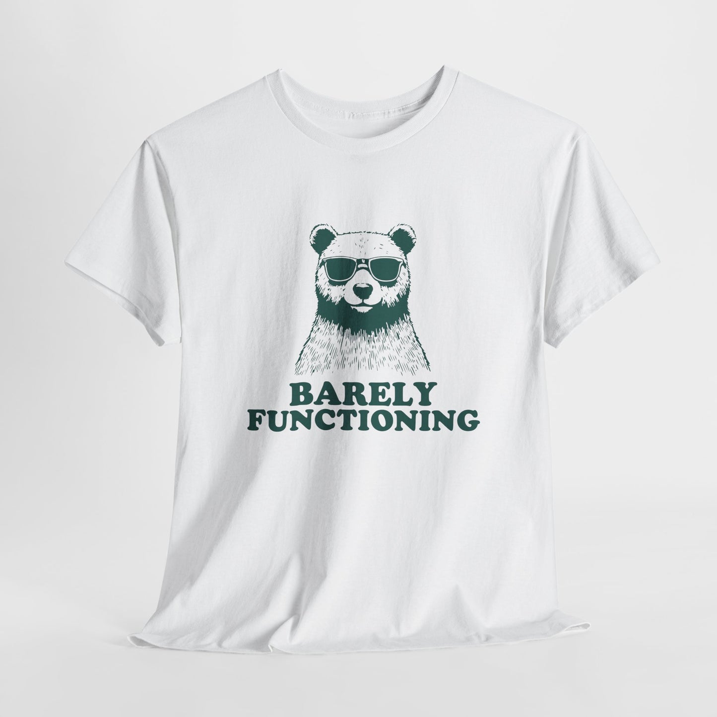 Hanging white T-shirt with a green bear graphic and "Barely Functioning" text. Part of the Vivid Divergence Sensory Friendly Unisex Tees Range.