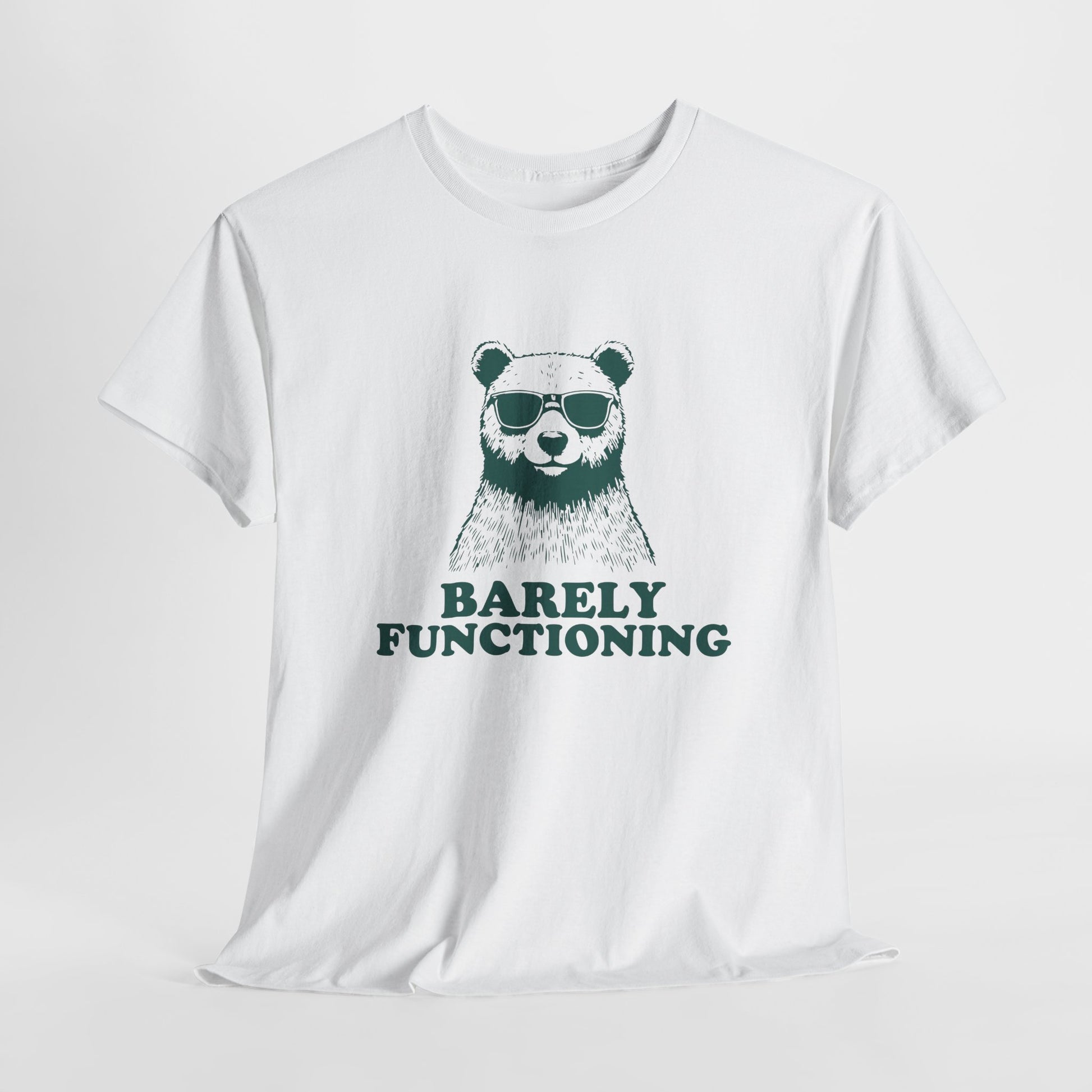 Hanging white T-shirt with a green bear graphic and "Barely Functioning" text. Part of the Vivid Divergence Sensory Friendly Unisex Tees Range.