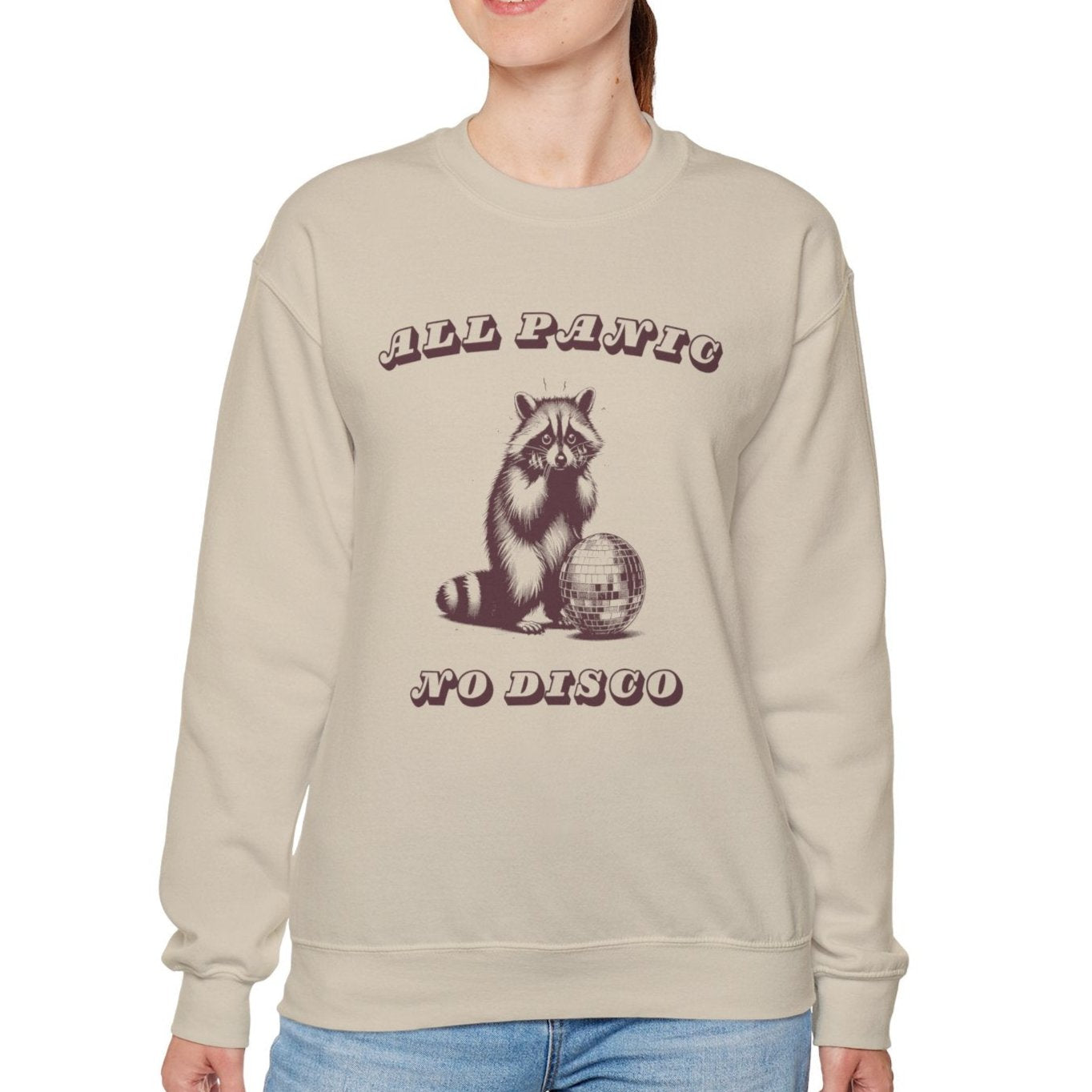 Model wearing a beige sweater jumper with a "All Panic No Disco" design featuring a raccoon illustration. Part of the Vivid Divergence Sensory Friendly Unisex Sweater Jumper Range.