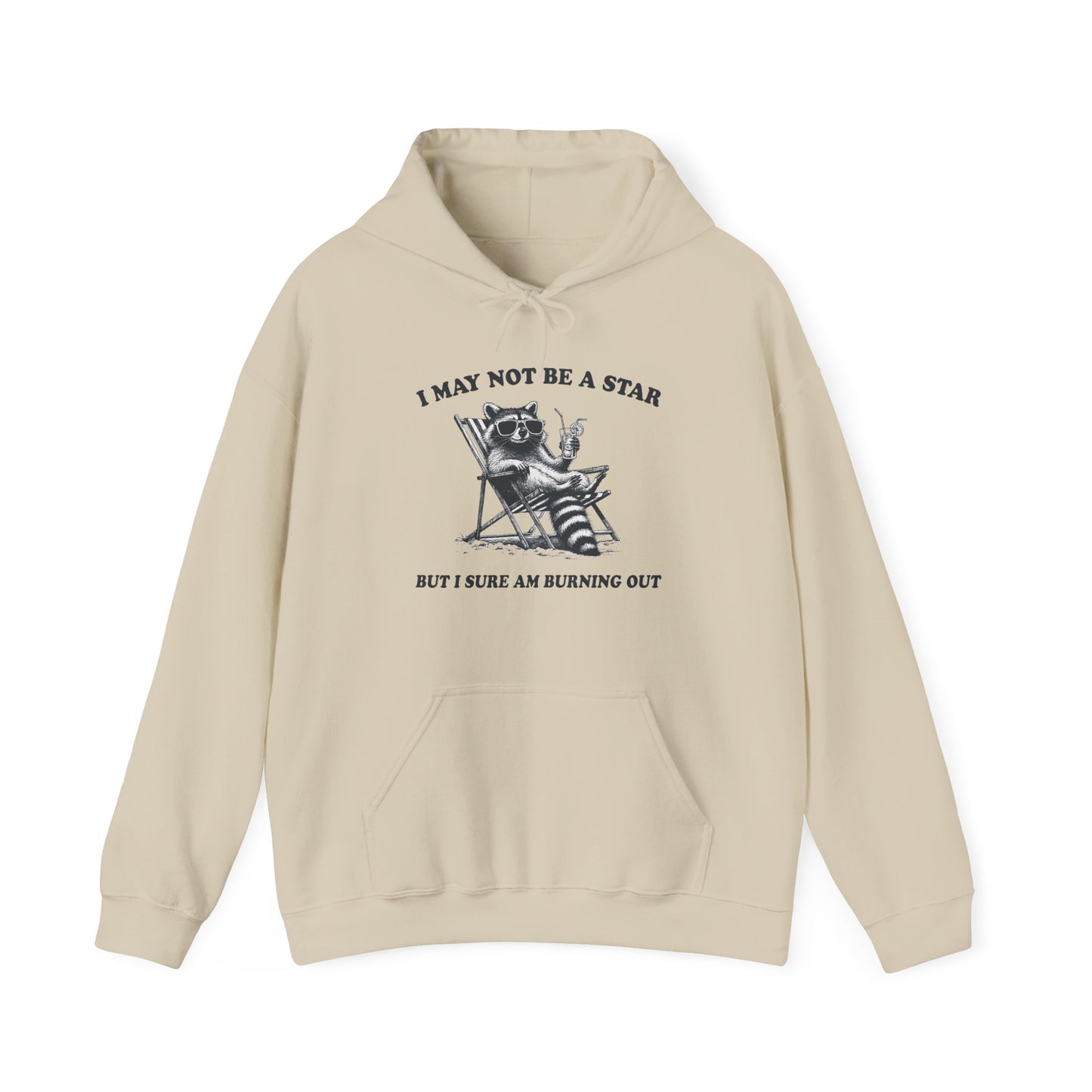 Front view of a beige hoodie featuring a raccoon sitting in a trash can with the text "I May Not Be A Star, But I Sure Am Burning Out." Part of the Vivid Divergence Sensory Friendly Unisex Hoodie Range.