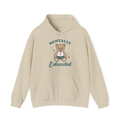 Front view of a beige hoodie featuring a cute teddy bear wearing an apron with the text "Mentally Exhausted." Part of the Vivid Divergence Sensory Friendly Unisex Hoodie Range.