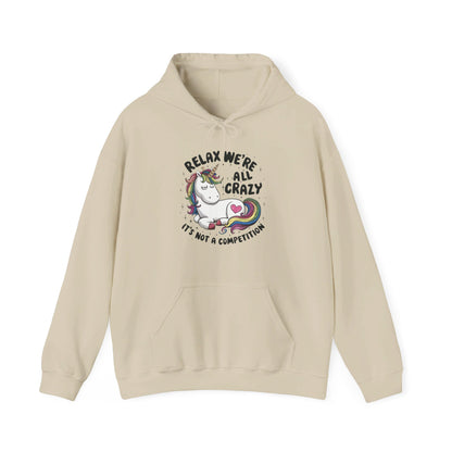 Front view of a beige hoodie featuring the text "Relax, We're All Crazy" and a cartoon illustration of a raccoon in a teacup. Part of the Vivid Divergence Sensory Friendly Unisex Hoodie Range.