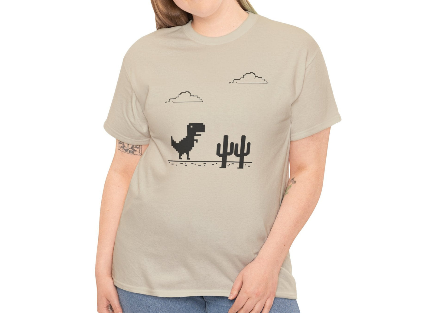 Model wearing a beige T-shirt featuring a minimalist pixel-style T-Rex Runner Dinosaur Game design with a T-Rex, cacti, and clouds. Part of the Vivid Divergence Sensory Friendly Unisex Tees Range.