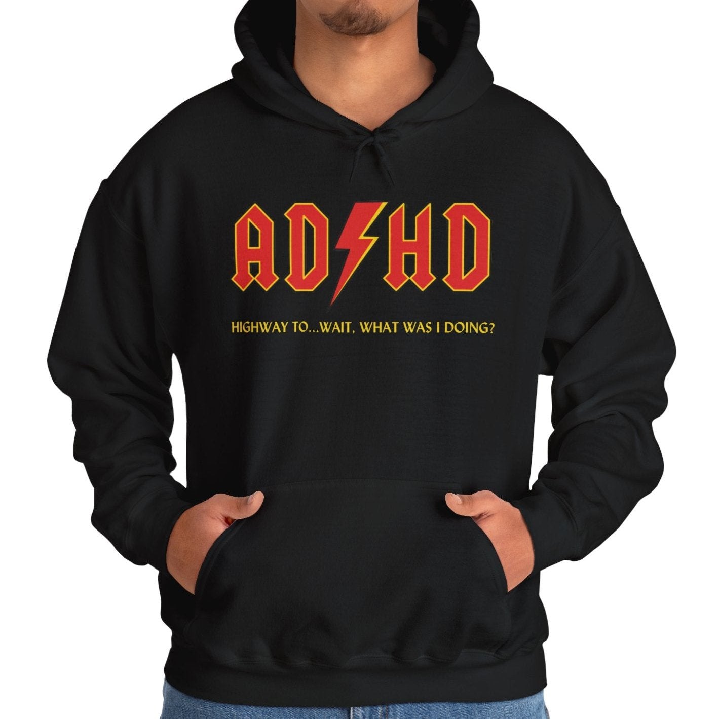 Model wearing a black hoodie with the text "ADHD" in AC/DC parody style bold orange lettering and "Highway to Hey, What Was I Doing?" underneath. Part of the Vivid Divergence Sensory Friendly Unisex Hoodie Range.