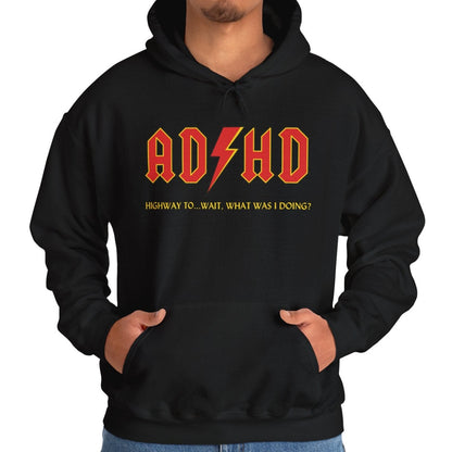 Model wearing a black hoodie with the text "ADHD" in AC/DC parody style bold orange lettering and "Highway to Hey, What Was I Doing?" underneath. Part of the Vivid Divergence Sensory Friendly Unisex Hoodie Range.