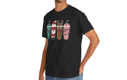 Model wearing a pink T-shirt featuring a festive illustration of four iced coffee cups decorated with Christmas designs, styled in a cozy indoor setting. Part of the Vivid Divergence Sensory Friendly Unisex Tees Range.
