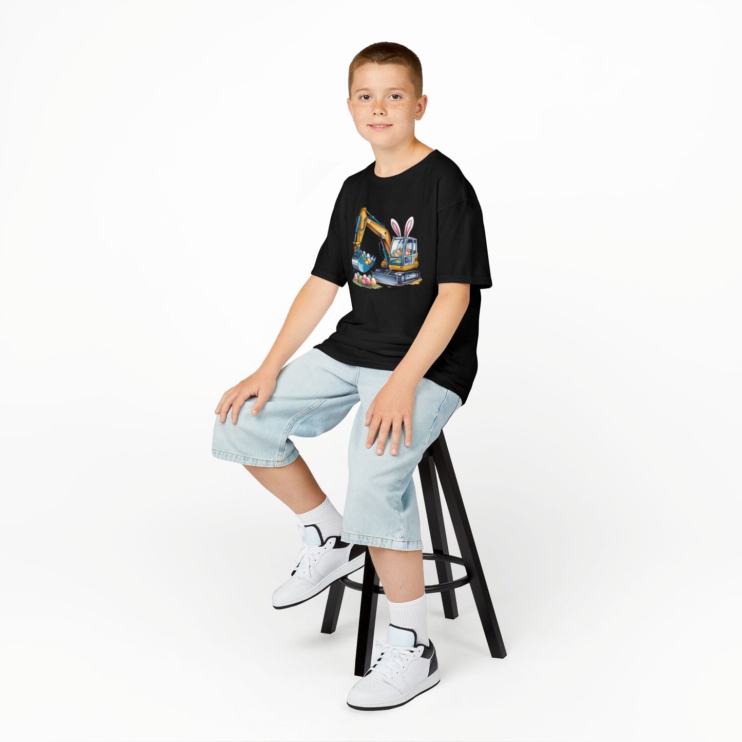 Child wearing a black Easter T-shirt featuring a construction excavator lifting eggs, a cool and unique holiday look. Hop into the season in style and shop Easter shirts online today!