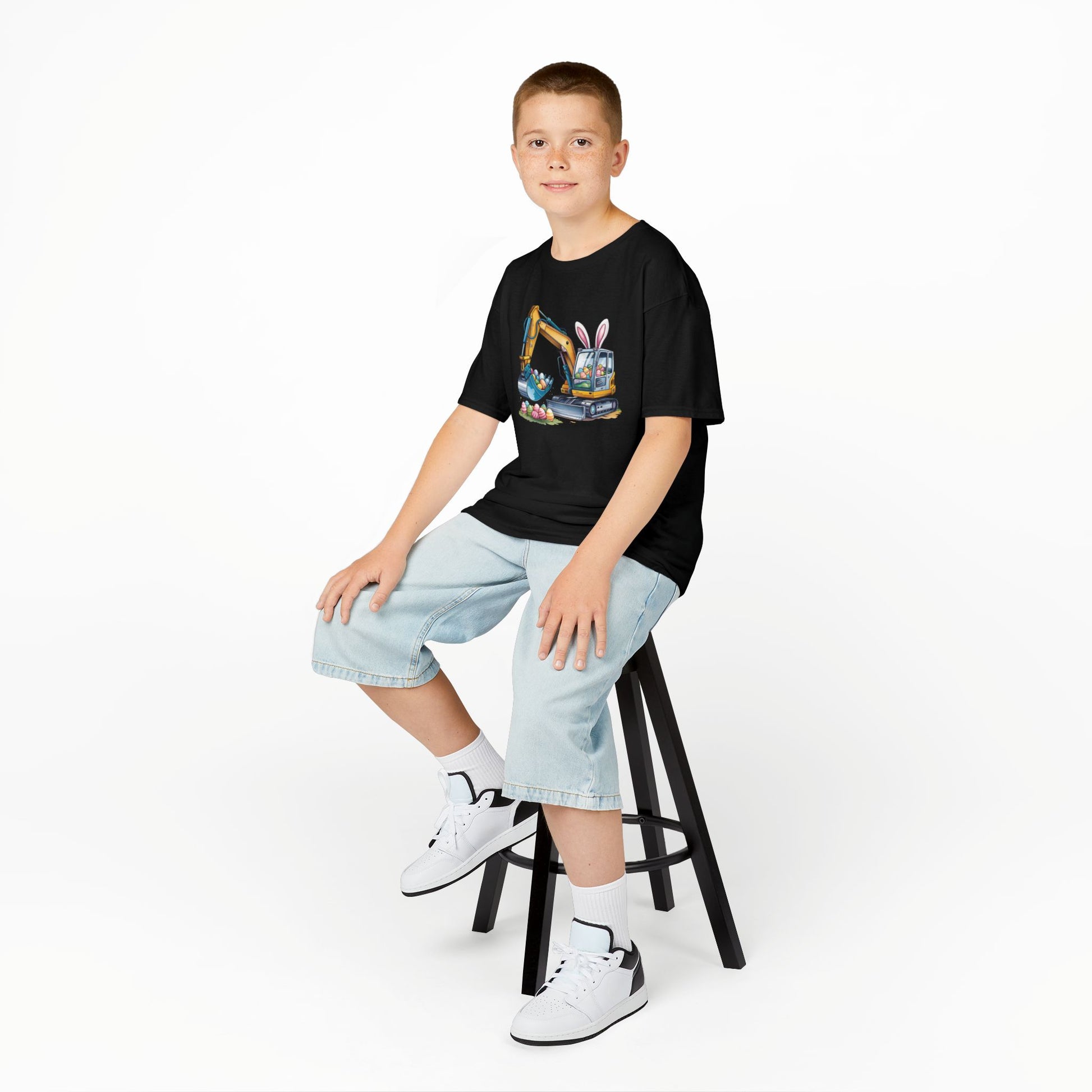 Child wearing a black Easter T-shirt featuring a construction excavator lifting eggs, a cool and unique holiday look. Hop into the season in style and shop Easter shirts online today!