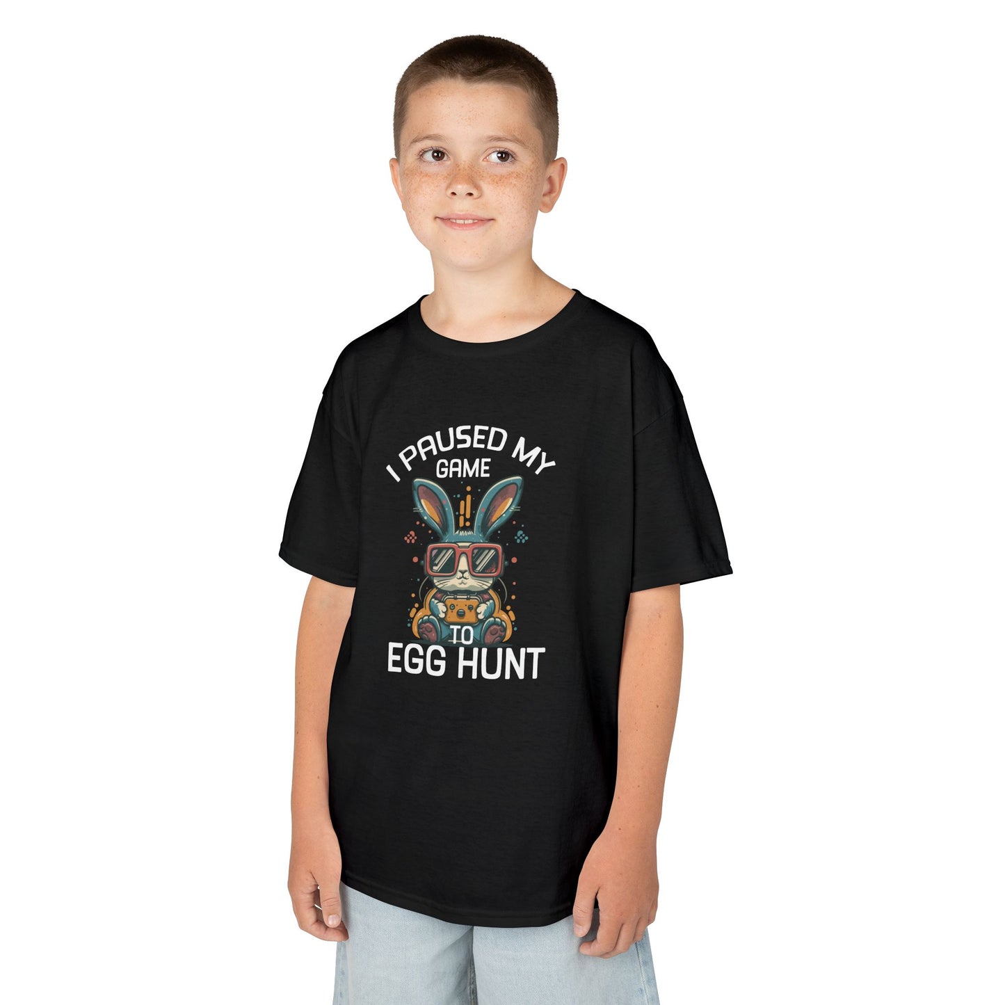 Child wearing a black Easter T-shirt with "I Paused My Game to Egg Hunt" and a gaming-style bunny, a fun and festive look for young gamers. Hop into the season in style and shop Easter shirts online today!