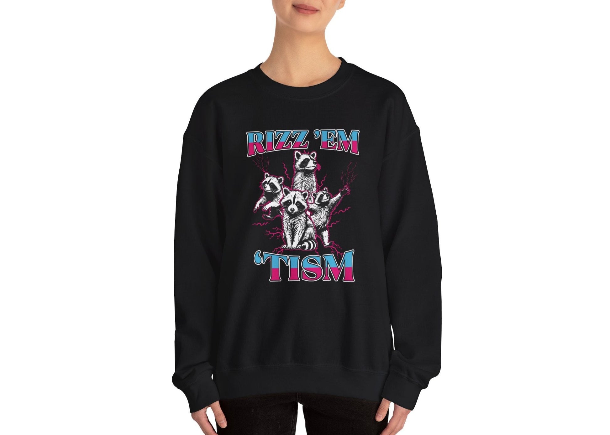 Model wearing a black sweater jumper with the text "Rizz 'Em 'Tism" and a cartoon raccoon illustration striking a pose. Part of the Vivid Divergence Sensory Friendly Unisex Sweater Jumper Range.
