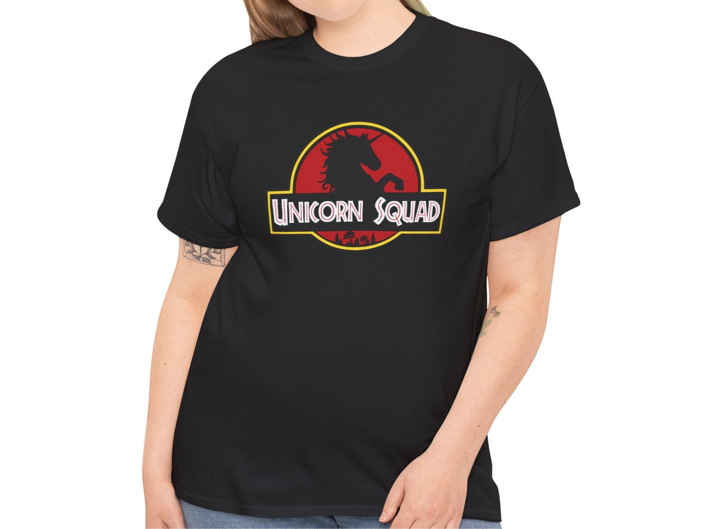 Model wearing a black T-shirt with "Unicorn Squad" in bold white text inside a red and yellow Jurassic Park-style logo, paired with casual jeans. Part of the Vivid Divergence Sensory Friendly Unisex Tees Range.