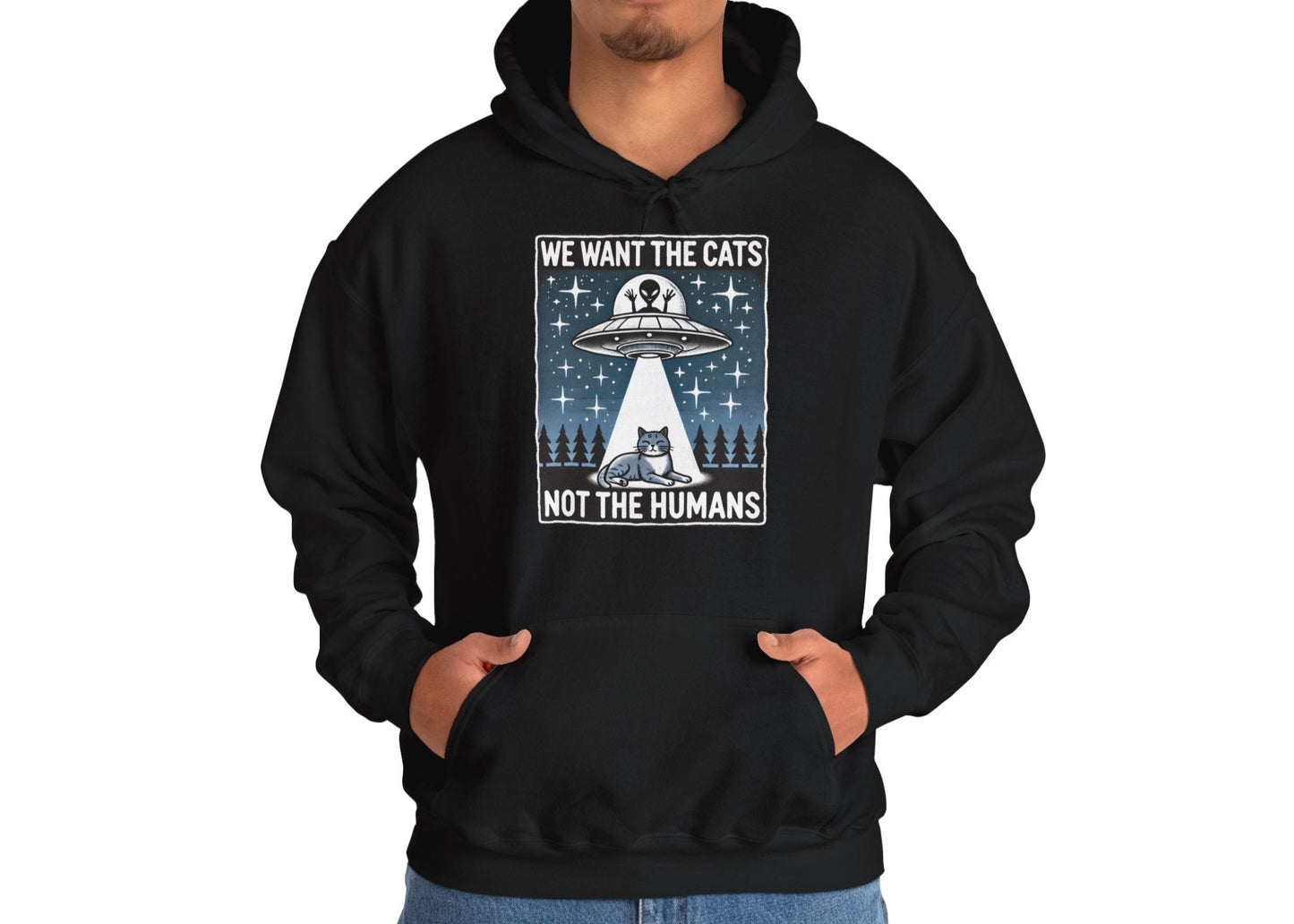 Model wearing a black hoodie featuring the text "We Want the Cats, Not the Humans" with an illustration of a UFO beaming up cats. Part of the Vivid Divergence Sensory Friendly Unisex Hoodie Range.