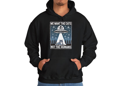 Model wearing a black hoodie featuring the text "We Want the Cats, Not the Humans" with an illustration of a UFO beaming up cats. Part of the Vivid Divergence Sensory Friendly Unisex Hoodie Range.