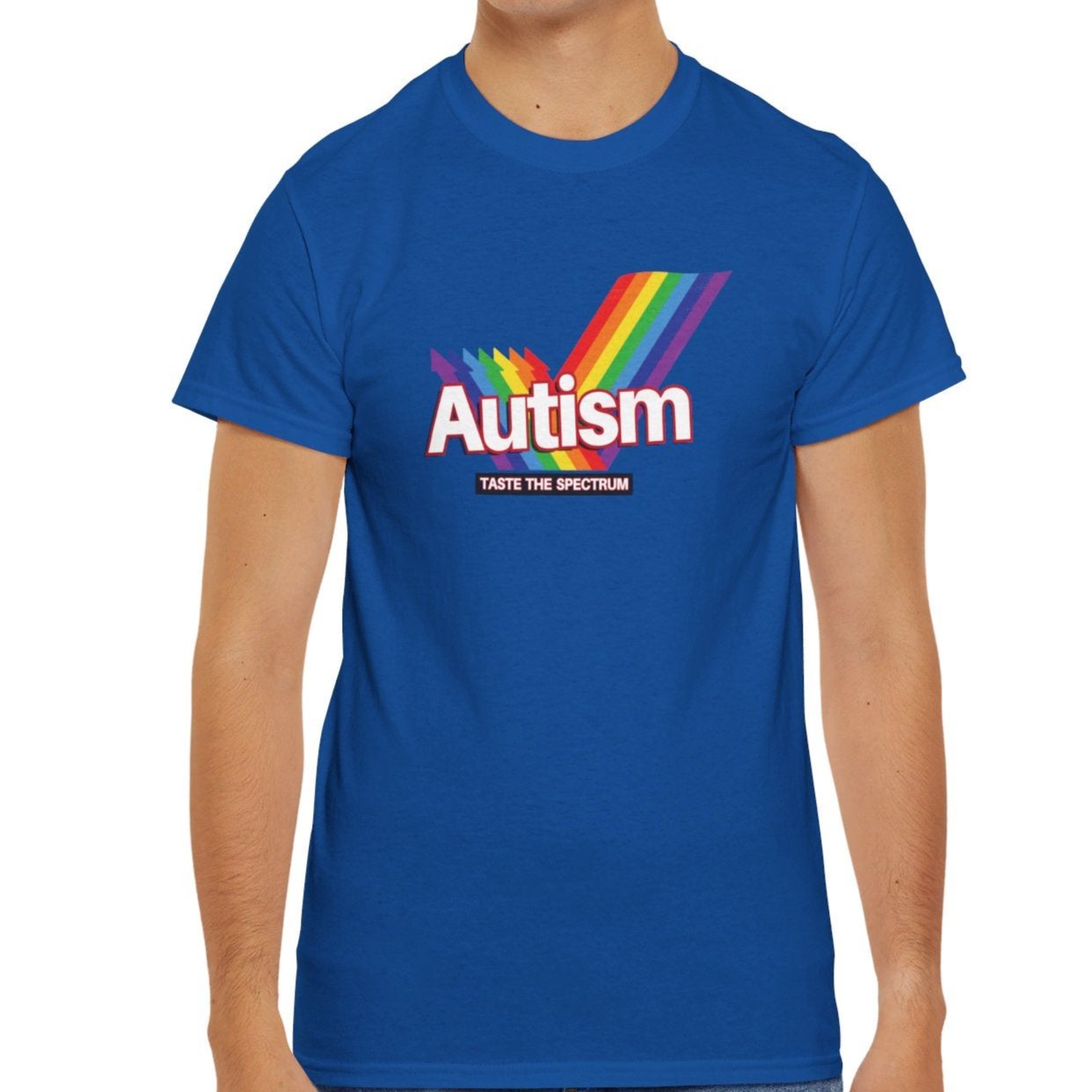 Modelled view of a blue T-shirt with the phrase "Autism" in a Skittles-inspired design featuring a rainbow graphic. Part of the Vivid Divergence Sensory Friendly Unisex Tees Range.