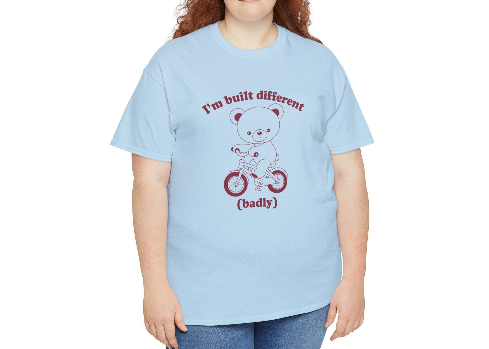 Model wearing a blue T-shirt with the "Built Different (Badly)" bear design. Part of the Vivid Divergence Sensory Friendly Unisex Tees Range.