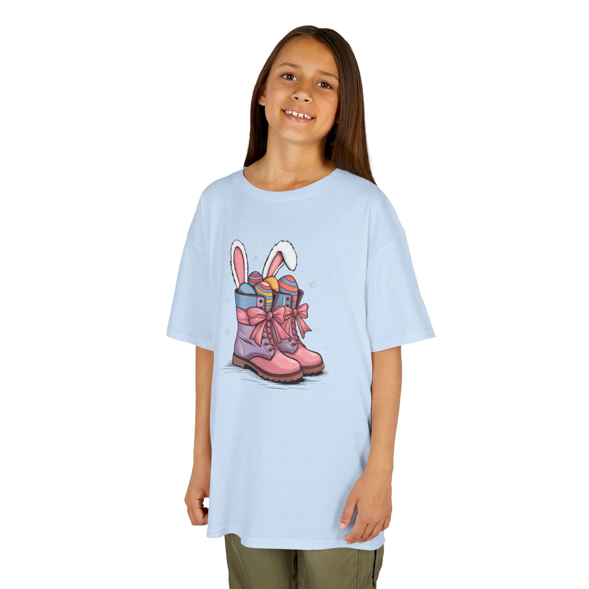 Child wearing a light blue Easter T-shirt with cowgirl boots, bunny ears, and festive eggs. A cute and trendy Easter outfit. Hop into the season in style and shop Easter shirts online today!