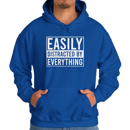 Model wearing a blue hoodie with the text "Easily Distracted by Everything" in bold white lettering. Part of the Vivid Divergence Sensory Friendly Unisex Hoodie Range.