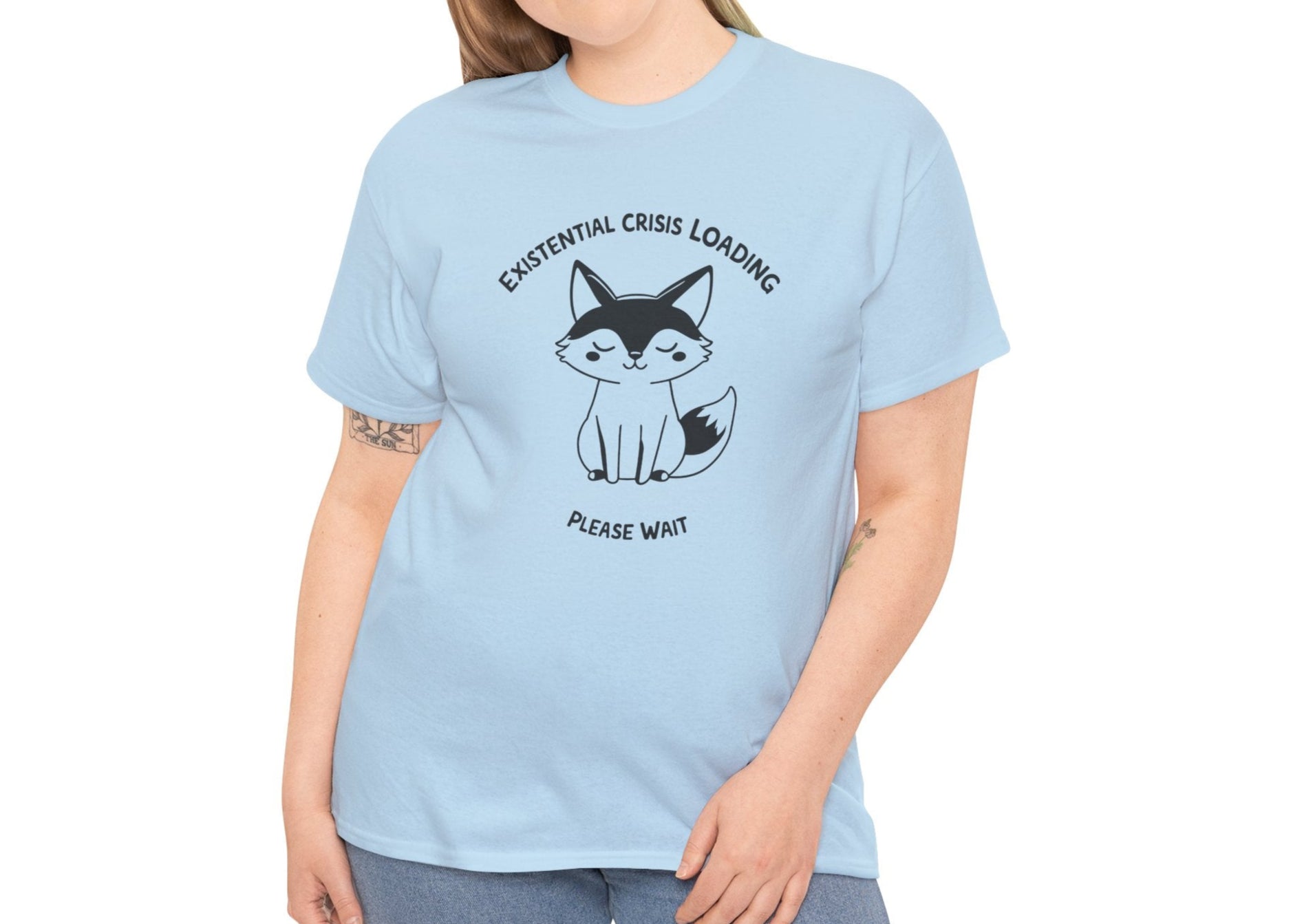 Woman wearing a light blue T-shirt with a black and white fox graphic and "Existential Crisis Loading, Please Wait" text. Part of the Vivid Divergence Sensory Friendly Unisex Tees Range.