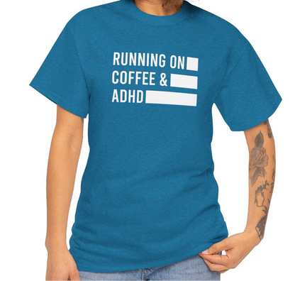 Model wearing a blue T-shirt with "Running on Coffee & ADHD" in bold white text. Part of the Vivid Divergence Sensory Friendly Unisex Tees Range.