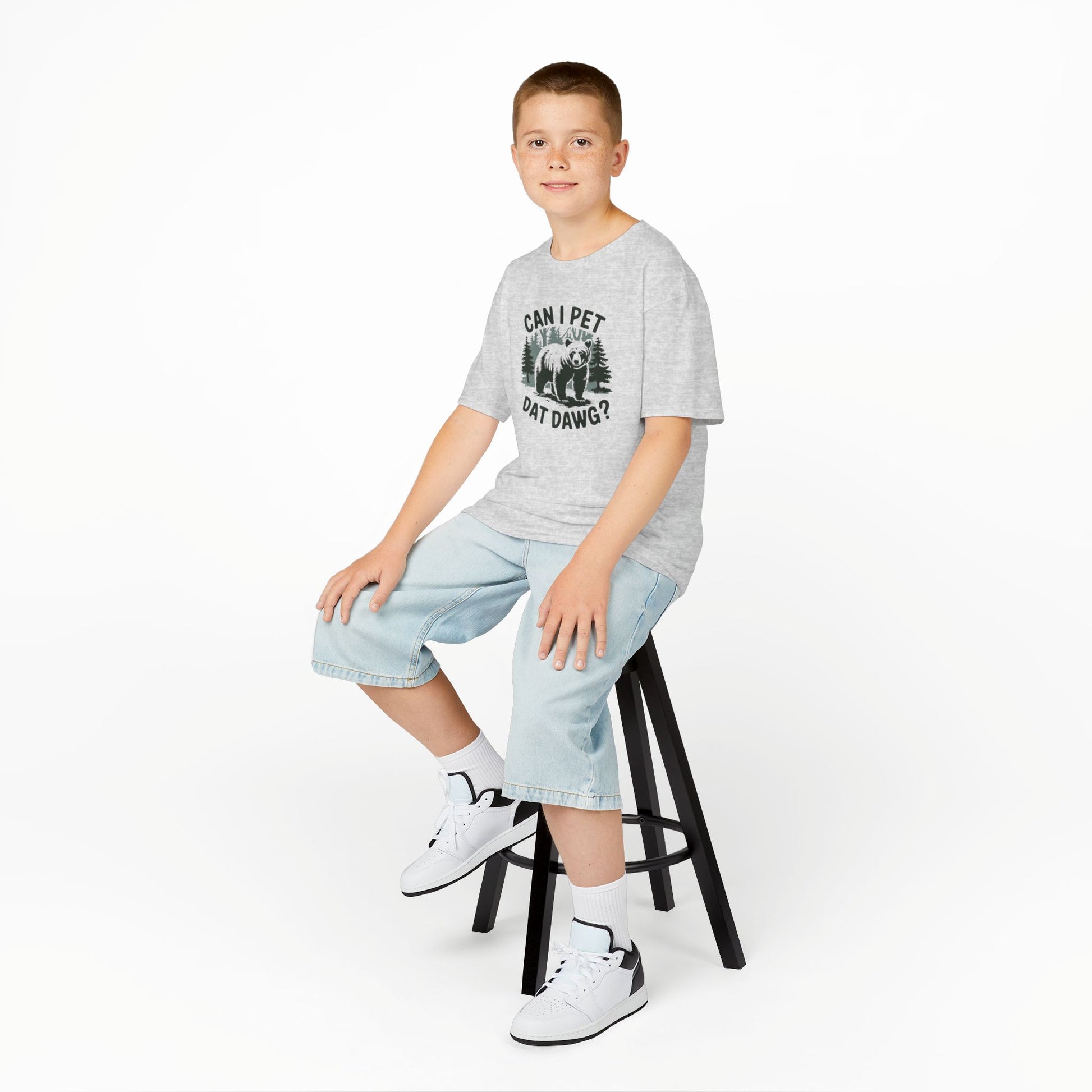 Boy sitting on a stool wearing a gray "Can I Pet Dat Dawg" meme kids T-shirt with a playful dog graphic. Part of the Vivid Divergence Sensory Friendly Kids Shirts Range. The perfect T-shirt for sensory-sensitive kids and comes with a Sensory Satisfaction Promise.