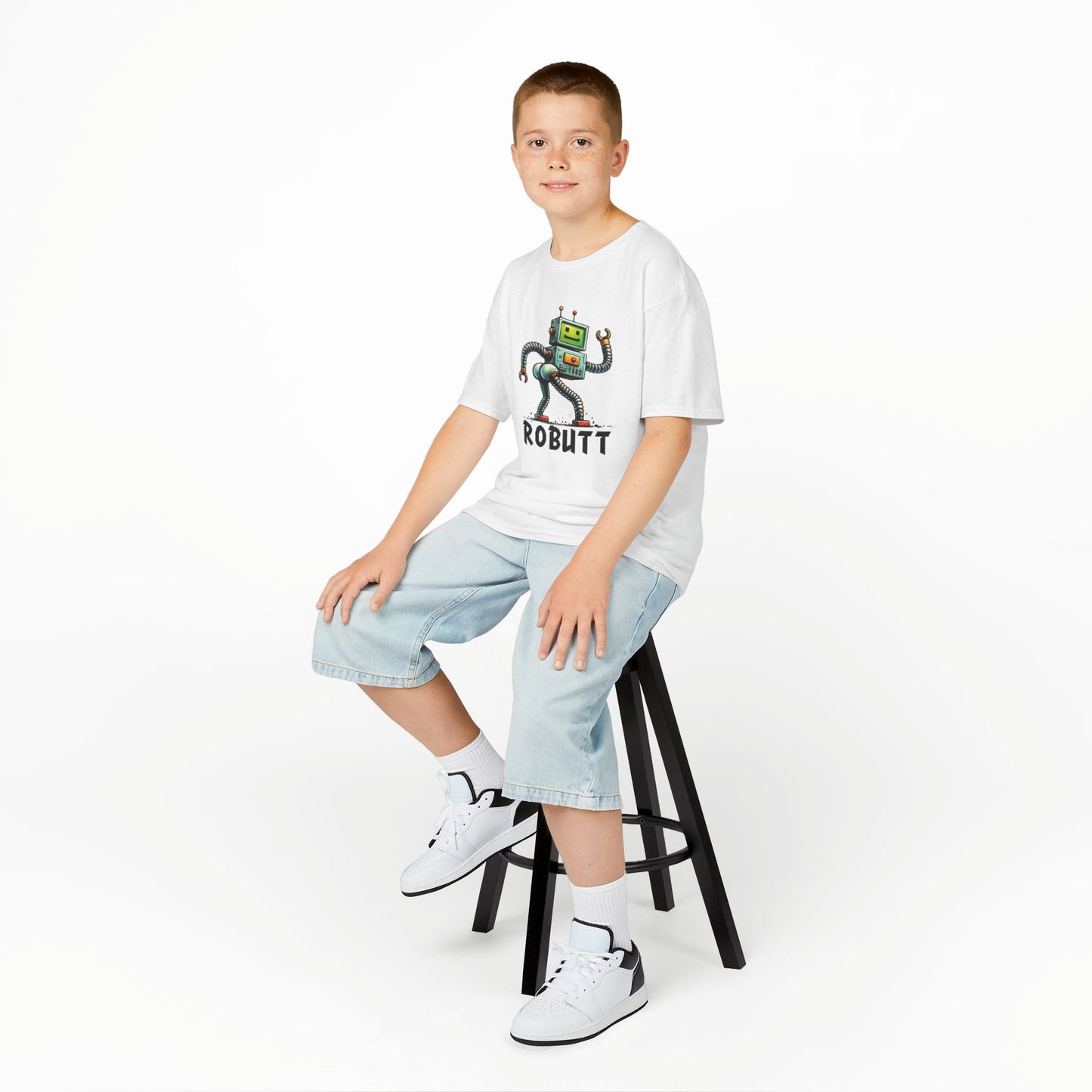 Boy sitting on a stool wearing a white "Robutt" robot shuffle kids T-shirt with a playful cartoon robot dancing. Part of the Vivid Divergence Sensory Friendly Kids Shirts Range. The perfect T-shirt for sensory-sensitive kids and comes with a Sensory Satisfaction Promise.