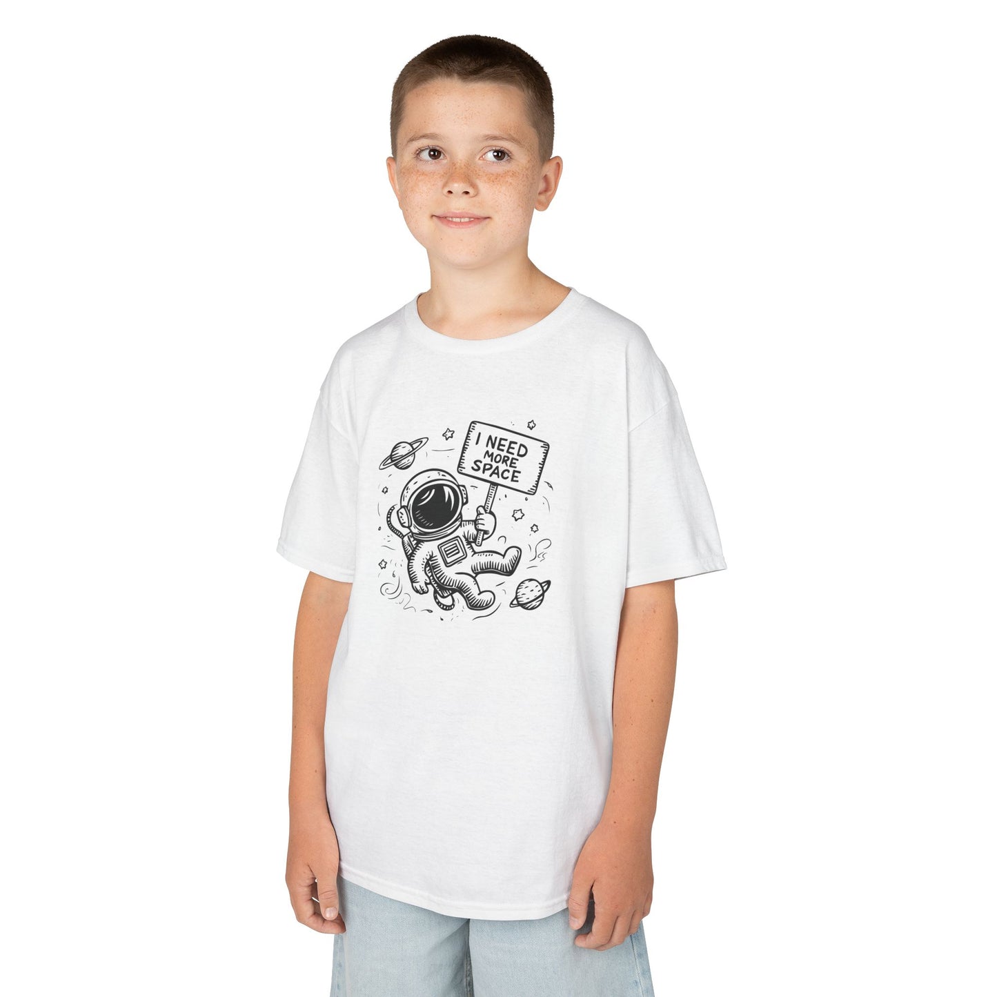 Boy wearing a white "I Need More Space" astronaut kids T-shirt with a cartoon astronaut floating among space icons. Part of the Vivid Divergence Sensory Friendly Kids Shirts Range. The perfect T-shirt for sensory-sensitive kids and comes with a Sensory Satisfaction Promise.