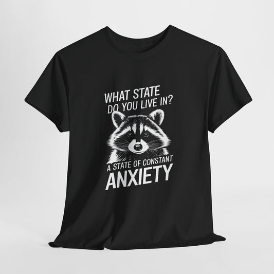 Hanging black T-shirt with a white raccoon graphic and the text "What state do you live in? A constant state of anxiety." Part of the Vivid Divergence Sensory Friendly Unisex Tees Range.