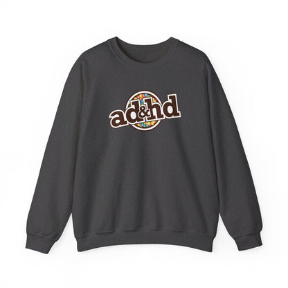 Flat-lay of a dark gray sweater jumper with an "ADHD" m&m brand parody design in brown and yellow tones. Part of the Vivid Divergence Sensory Friendly Unisex Sweater Jumper Range.