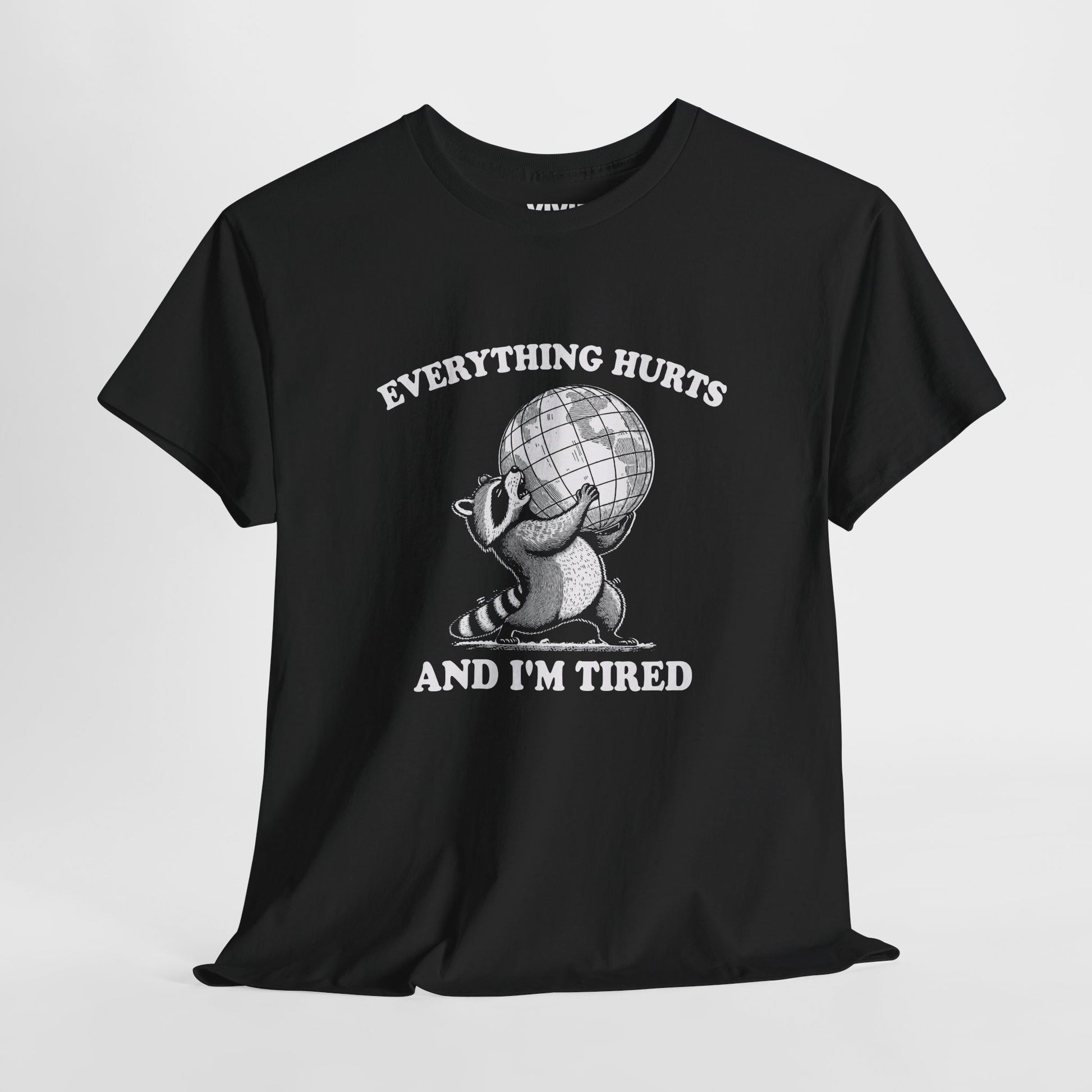 Hanging view of black T-shirt featuring a vintage style sketch of a raccoon carrying the world with the phrase “Everything Hurts and I’m Tired.” The official uniform of burnt out. Part of the Vivid Divergence Memewear Collection!
